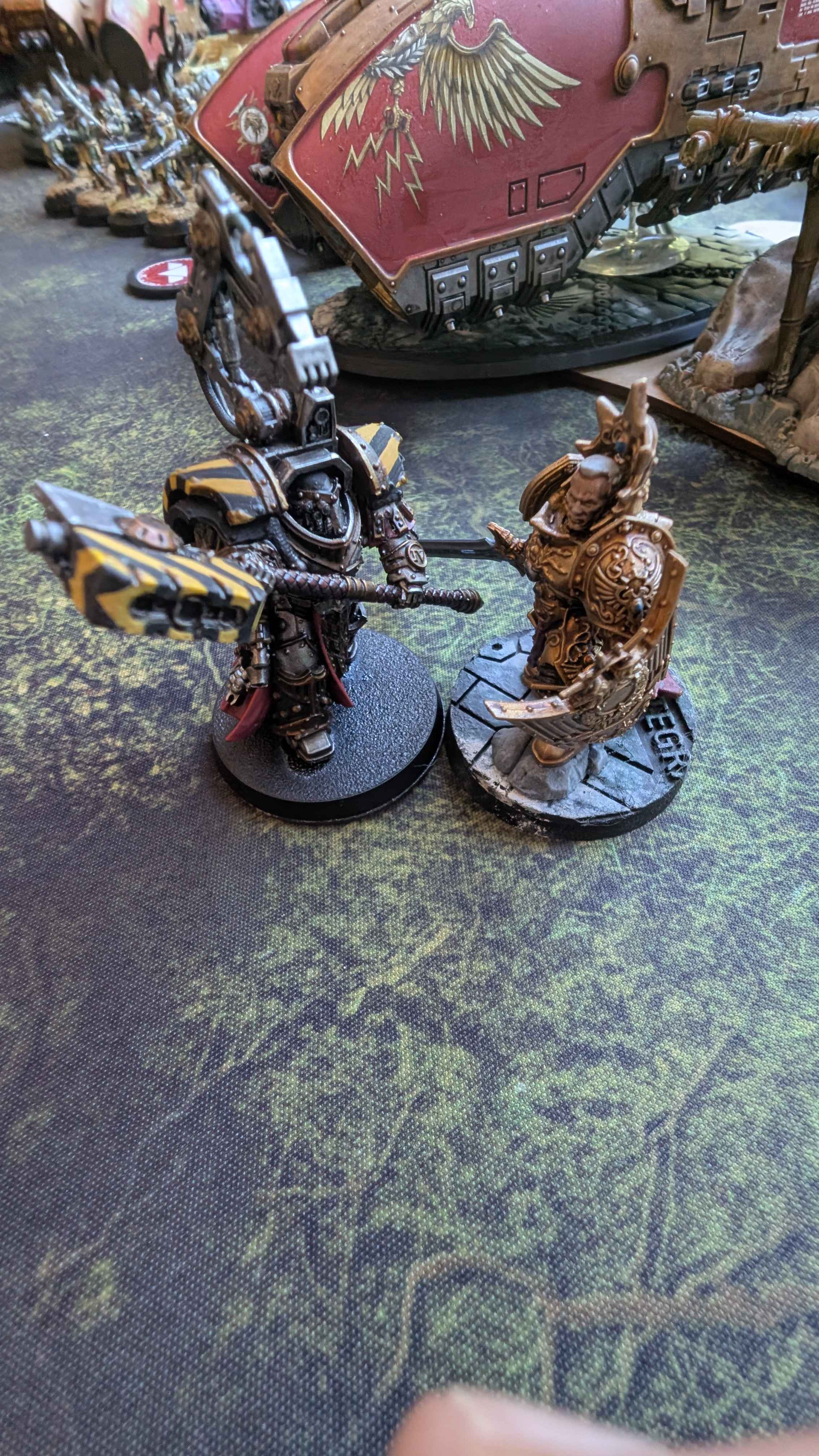 An Iron Warriors character duels a golden-armoured Custodian across a ruined battlefield