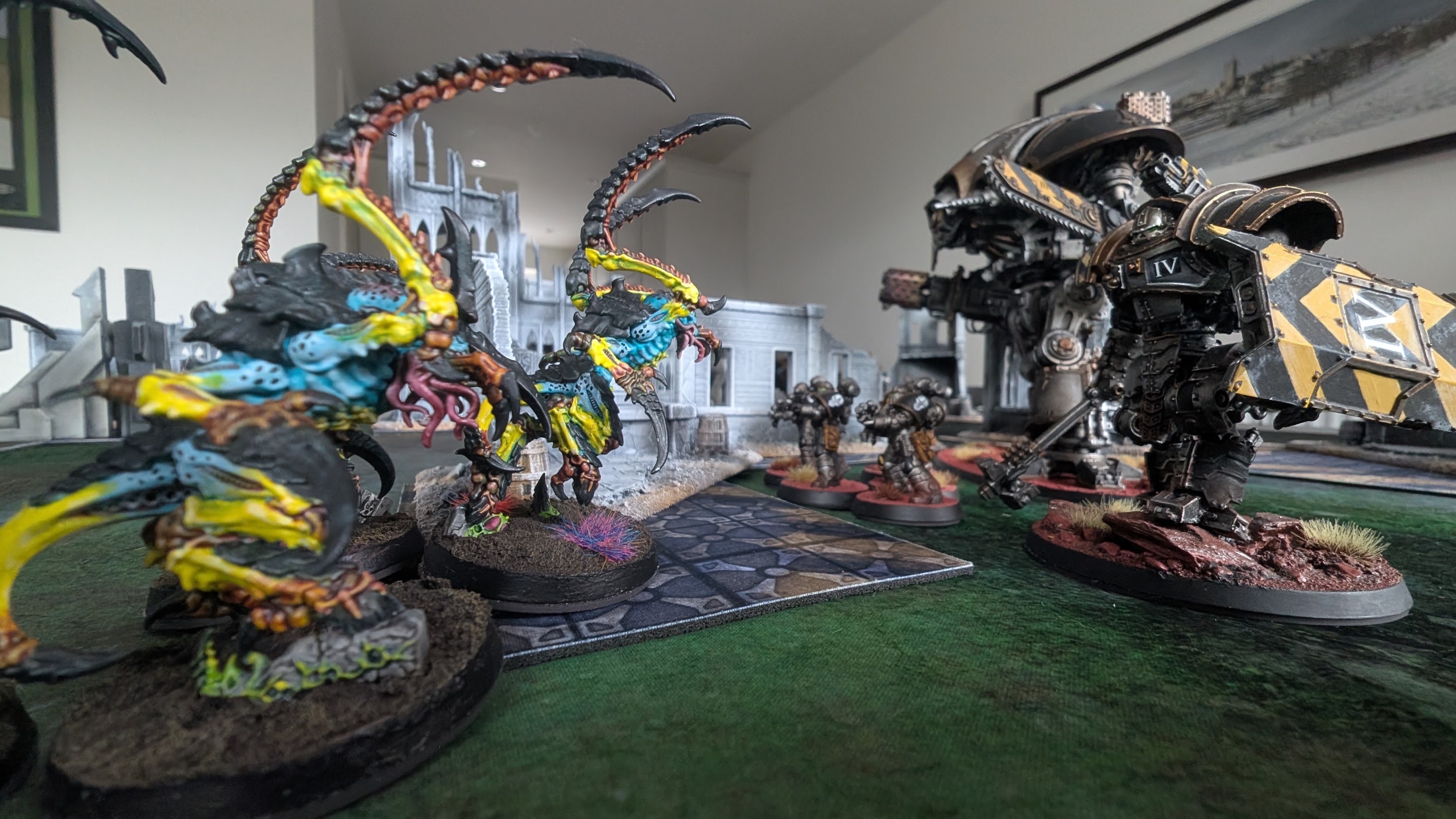 A hazard-striped Iron Warriors daemon engine advances on a line of winged Tyranids