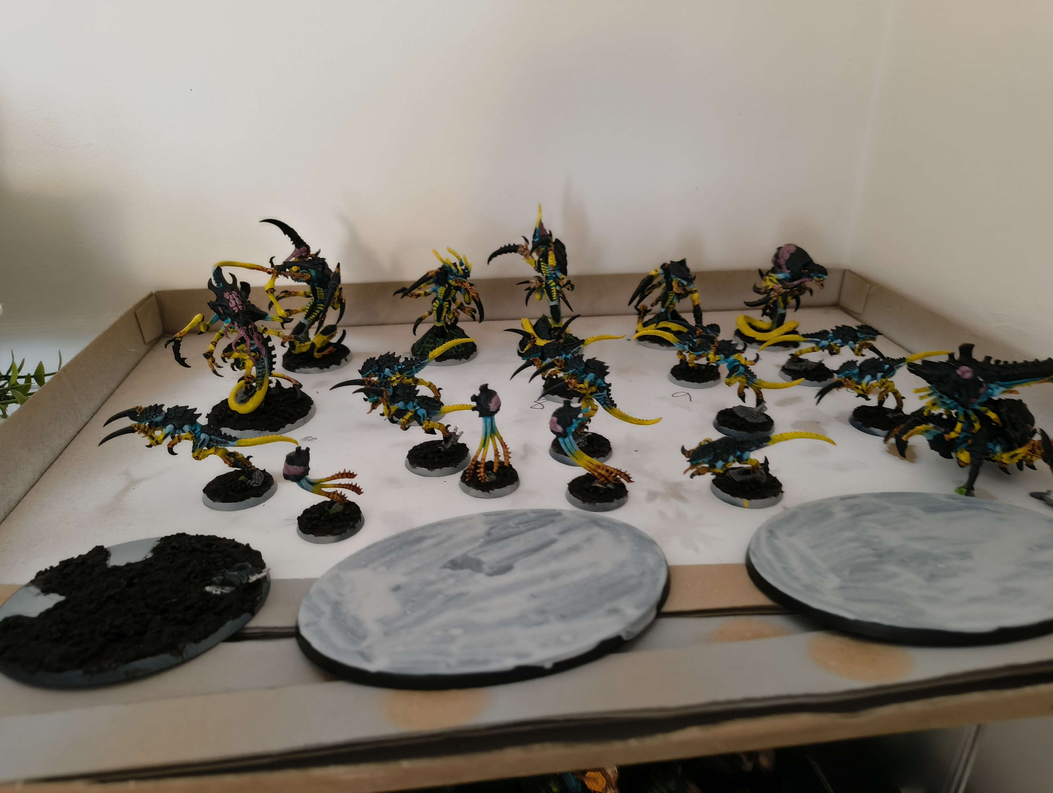 A tray of finished Tyranids with completed dark earth bases, blank bases waiting in front