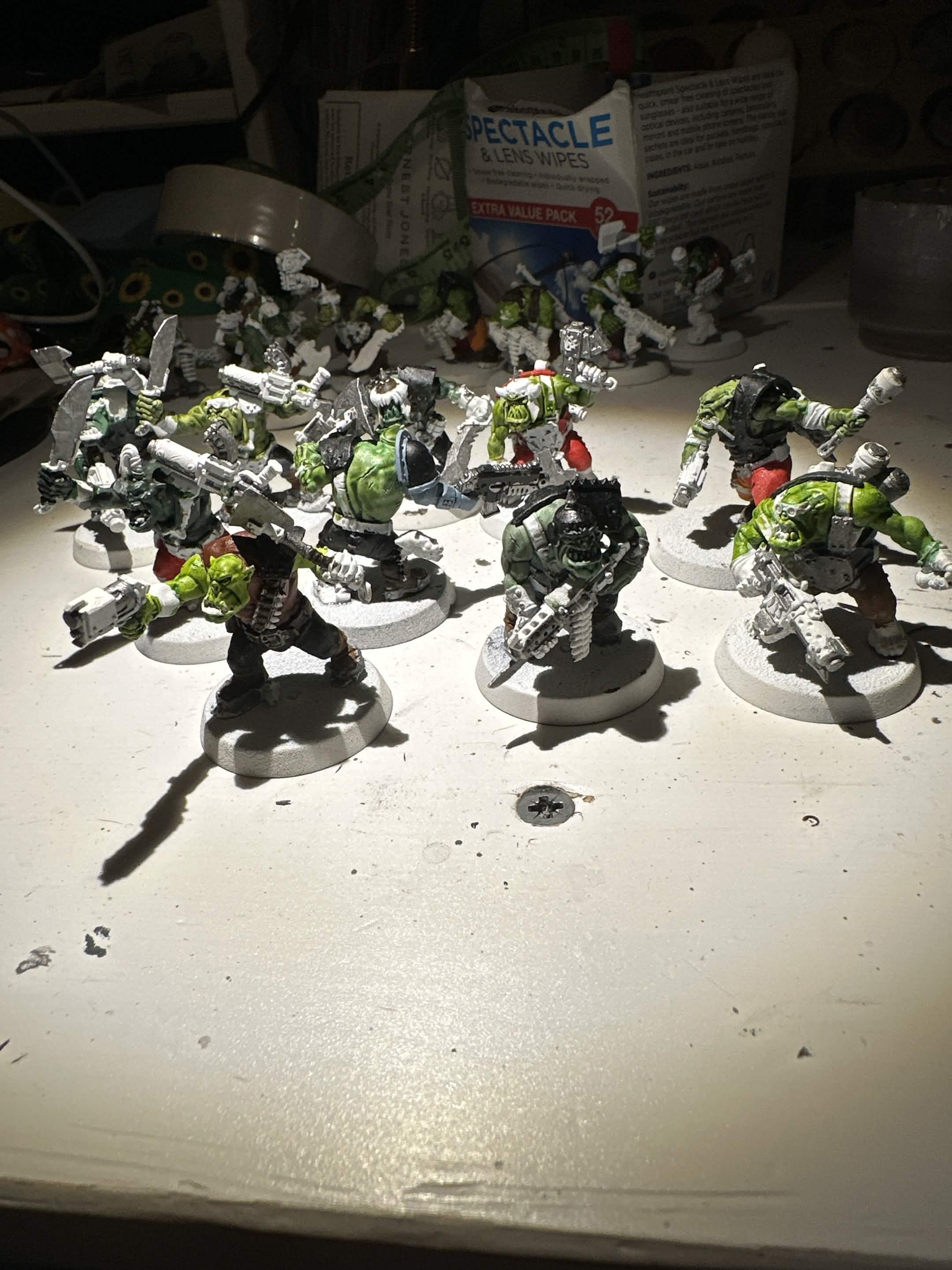 Ork Boyz part-painted in green contrast paint with bare metal weapons on white bases